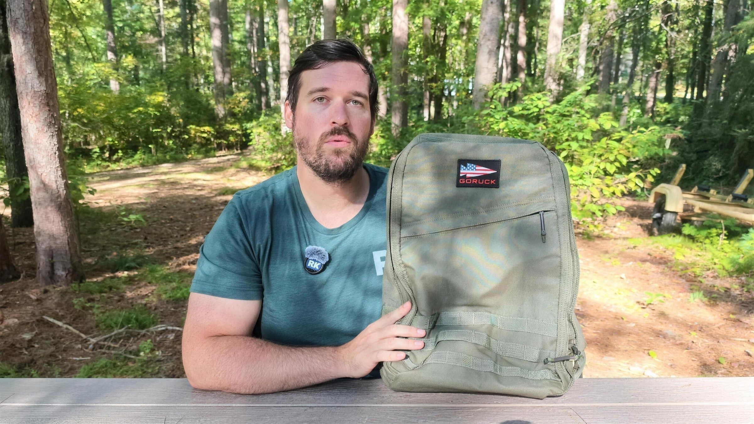 Me at a woodland picnic table with the green 26L GR1, filming this review