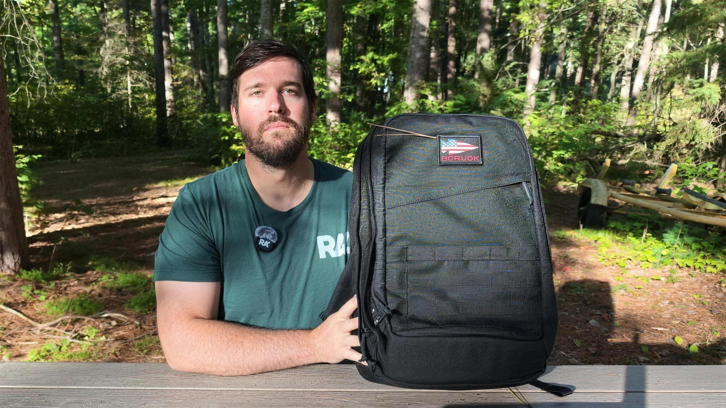 Me at a woodland picnic table with the black GR2 34L, filming this review