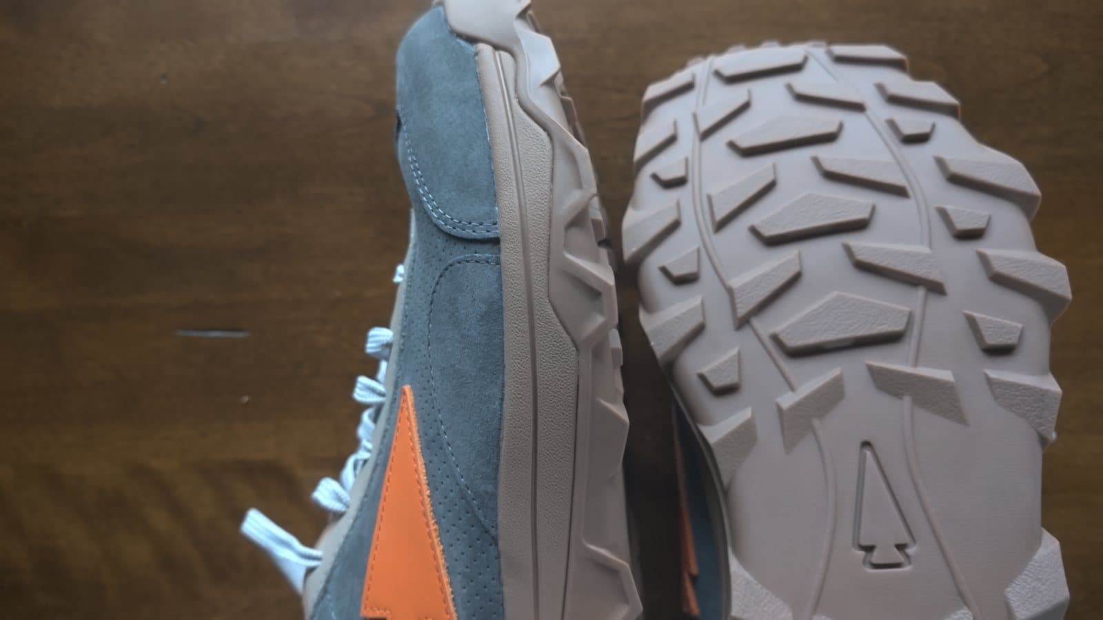 One Mackall 45 on its side next to the other upside down, showing the lugged outsole and the leather spearhead