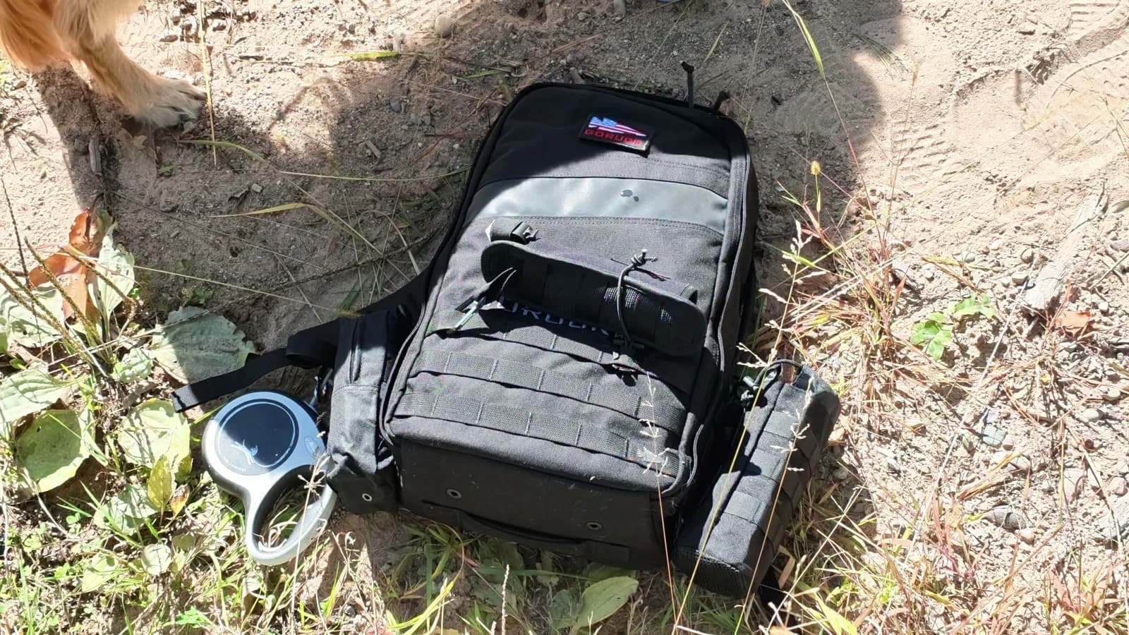 The loaded Rucker resting beside the trail with pouches and dog-walking accessories attached