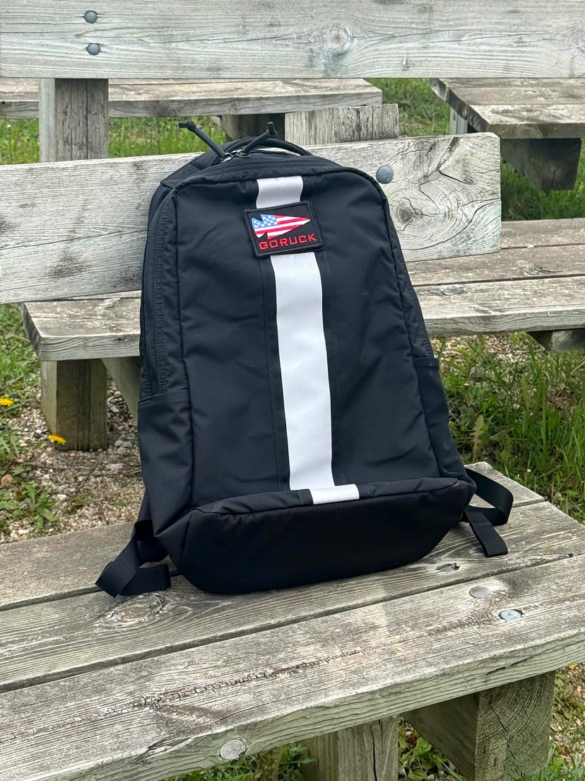GORUCK Basic Rucker auf verwitterten Stegplanken im Kohler-Andrae State Park - weißer Reflexionsstreifen und GORUCK-Amerika-Flaggen-Aufnäher, sauber und unbeschadet nach 12 Tagen Reisenutzung