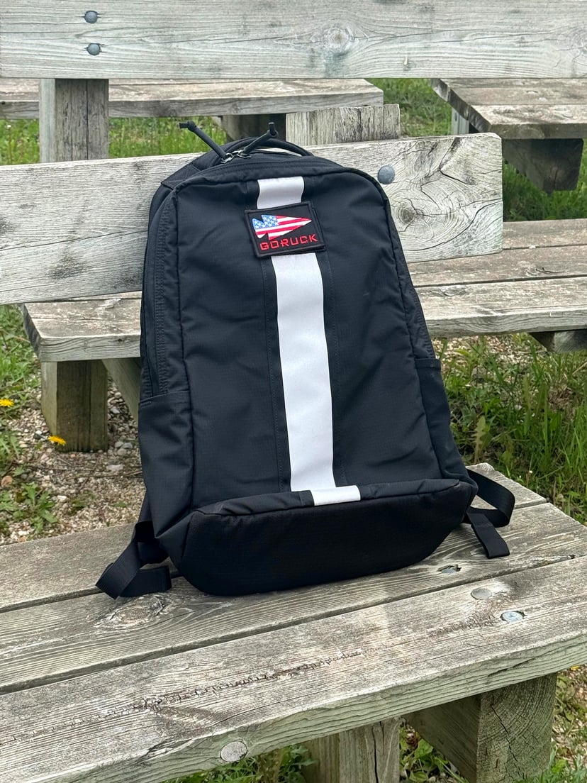GORUCK Basic Rucker on weathered boardwalk planks at Kohler-Andrae State Park - white reflective stripe and GORUCK American flag patch, clean and unaffected after 12 days of trip use