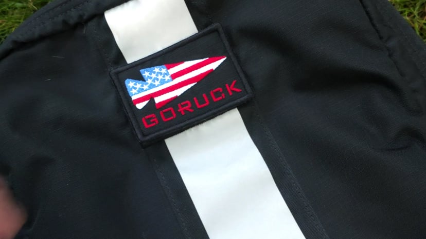 Close-up of the GORUCK flag patch above the white reflective stripe on a black Basic Rucker