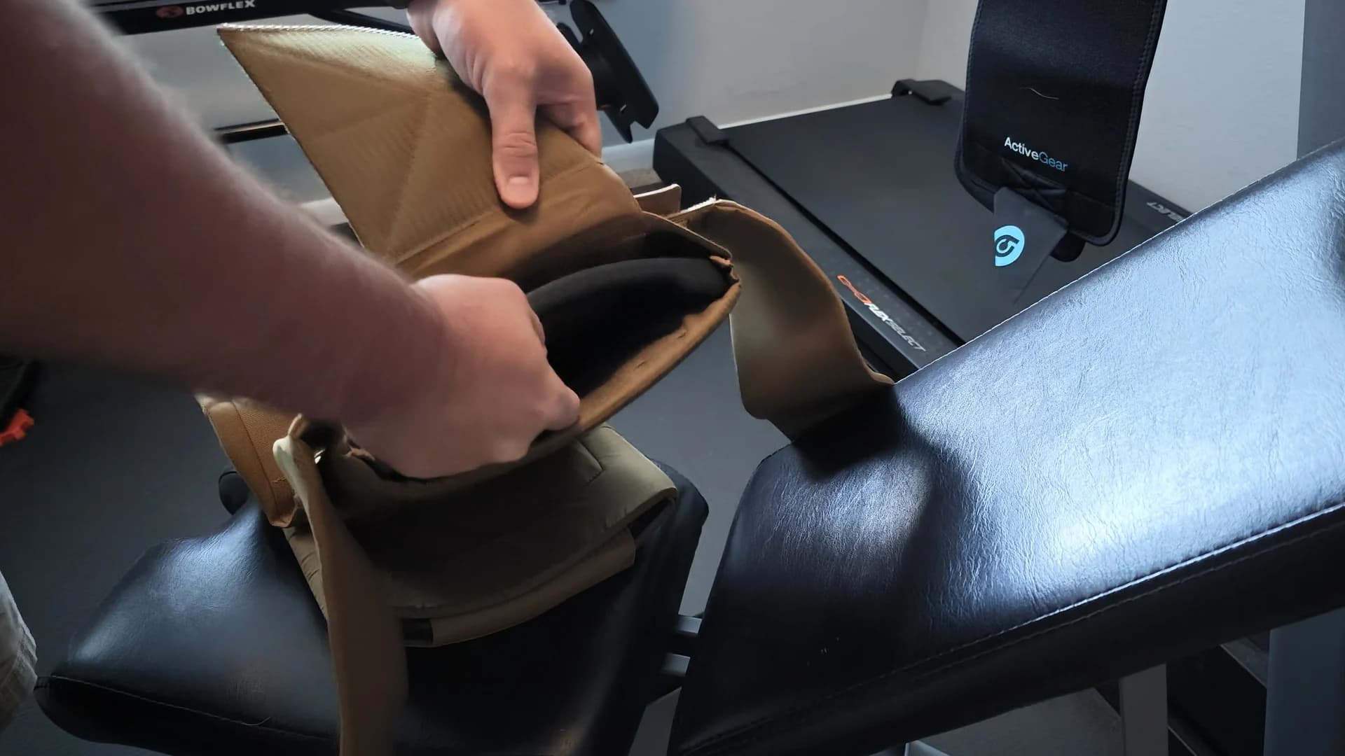 Inserting a curved plate into the open vest on a weight bench